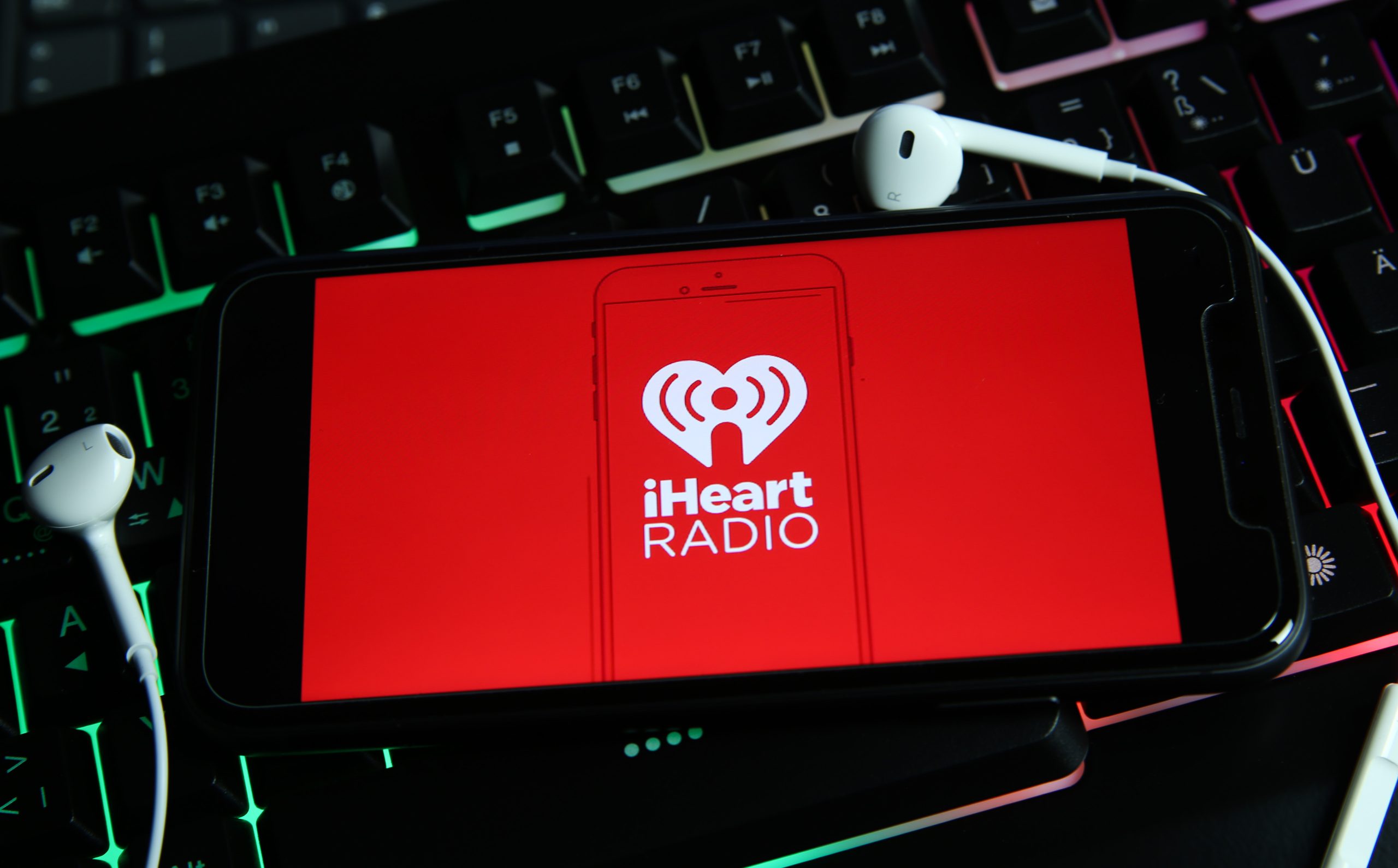 Viersen, Germany - January 9. 2021: Closeup of smartphone screen with logo lettering of online radio podcast streaming service iheart on computer keyboard