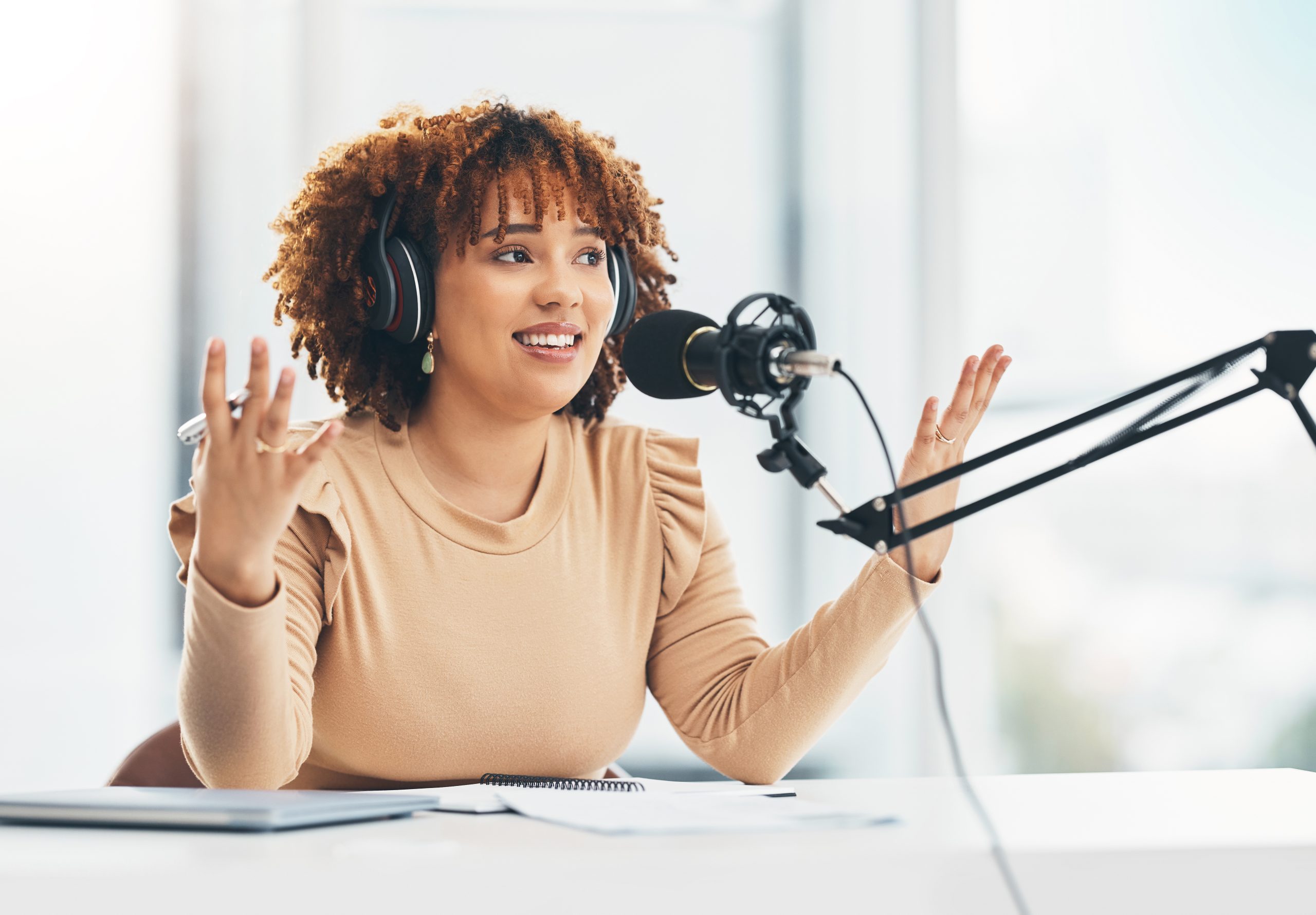 Radio show, podcast and black woman with microphone, talking and live streaming for advice. African American female presenter, lady or influencer with headphones, discussion or broadcast in workplace.
